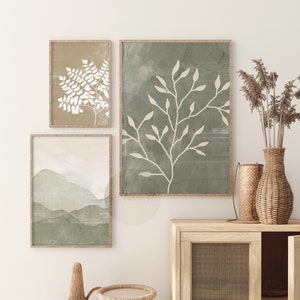 May include: Three framed prints with abstract botanical illustrations in shades of green and white. The prints are hung on a white wall above a wooden cabinet with a woven rattan door.