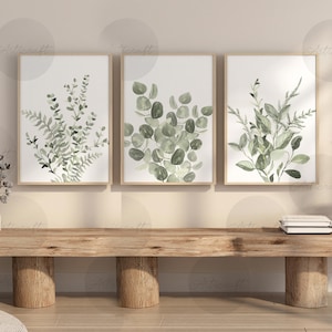 Puede incluir: Tres impresiones bot&aacute;nicas enmarcadas con ilustraciones en acuarela de eucalipto verde y otro follaje. Las impresiones se exhiben en un banco de madera, creando una est&eacute;tica natural. La obra de arte a&ntilde;ade un toque de naturaleza a cualquier interior.
