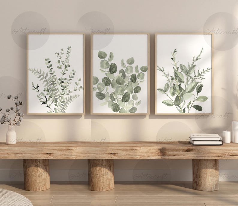 Puede incluir: Tres impresiones bot&aacute;nicas enmarcadas con ilustraciones en acuarela de eucalipto verde y otro follaje. Las impresiones se exhiben en un banco de madera, creando una est&eacute;tica natural. La obra de arte a&ntilde;ade un toque de naturaleza a cualquier interior.