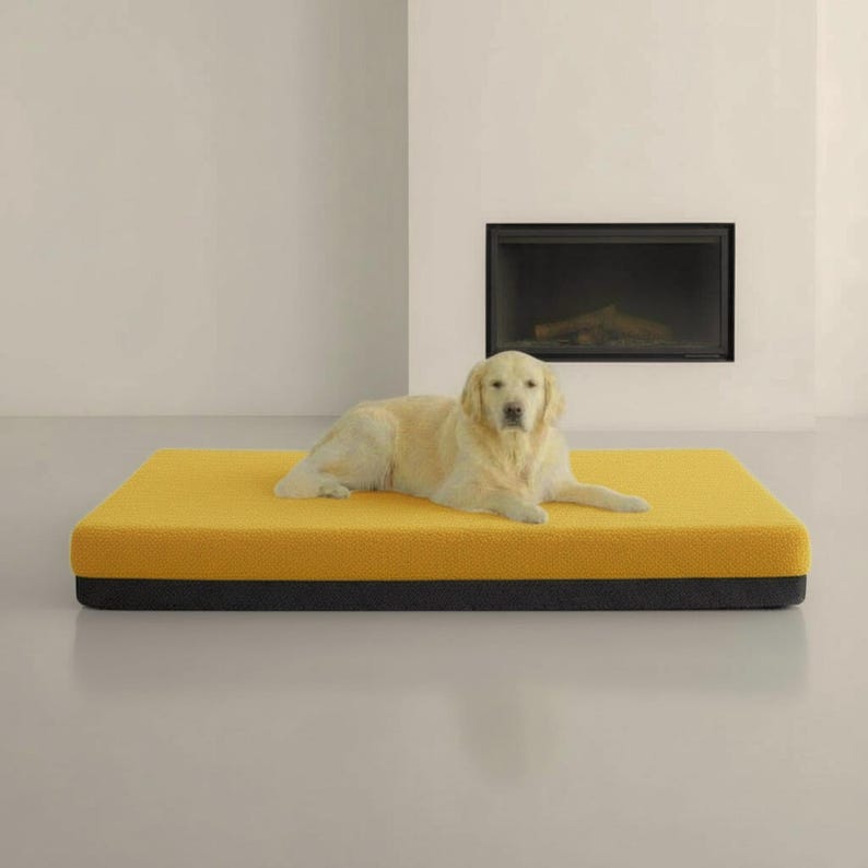 May include: A golden retriever dog rests on a rectangular yellow and black pet bed. The bed is a solid color with a textured surface. The dog is light tan and is lying down.