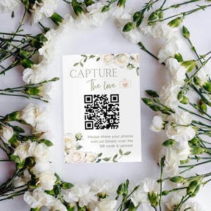 Może przedstawiać: Biała karta z kwiatowym wzorem i kodem QR. Tekst na karcie brzmi: "Capture the love. Podziel się swoimi zdjęciami z nami! Po prostu zeskanuj kod QR i prześlij."