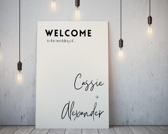 May include: White welcome sign with black text that reads "Welcome to the wedding of... Cassie + Alexander".