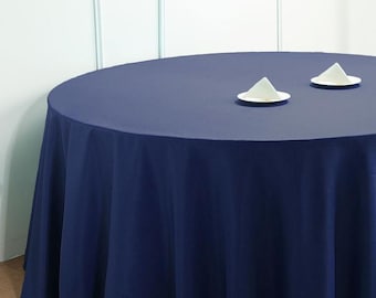 May include: A round navy blue tablecloth with two white folded napkins on white saucers.