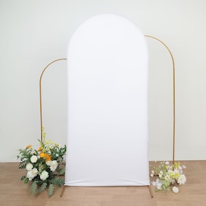 May include: A white backdrop with a rounded top, standing on a gold metal archway. The backdrop is perfect for photography and events.