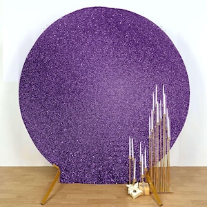 May include: A large, round, purple glitter backdrop with gold-colored support legs. A gold candelabra with white candles and small gift boxes are in front of the backdrop. The backdrop is suitable for events.