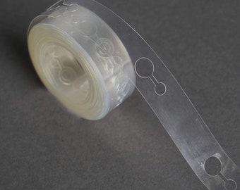 May include: A roll of clear balloon arch tape with evenly spaced holes for attaching balloons. The tape is rolled up and a section is extended to show the holes.