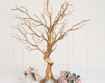 May include: Gold branch centerpiece with crystal strands hanging from the branches. Two bouquets of pink flowers are on either side of the centerpiece.