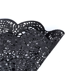 Puede incluir: Doily de encaje negro con borde festoneado. El doily est&aacute; hecho de un patr&oacute;n delicado e intrincado.