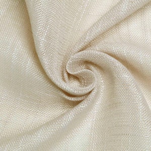 May include: A close-up of a beige fabric with a woven texture. The fabric is folded and draped, creating a soft and flowing look.