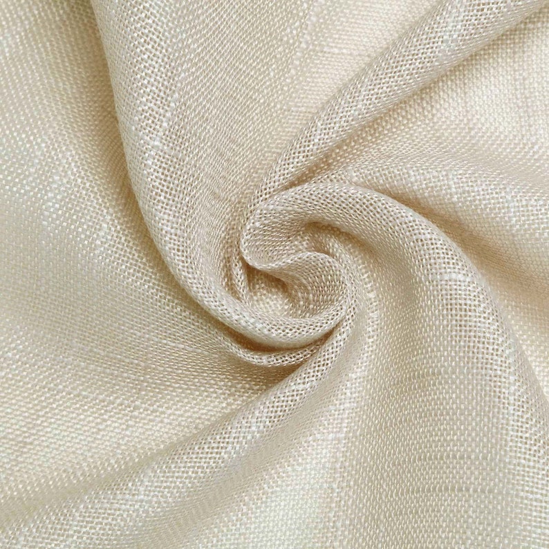 May include: A close-up of a beige fabric with a woven texture. The fabric is folded and draped, creating a soft and flowing look.