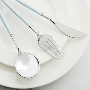 May include: A set of three silver-toned utensils with light blue handles. The set includes a fork, knife, and spoon.