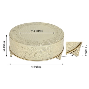 May include: Gold round cake stand with an ornate design. The stand measures 18 inches in diameter, 11.5 inches across the top, and 5.5 inches tall.