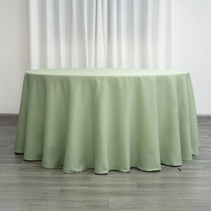 Op de afbeelding: Een ronde, saliegroene tafelkleed. Het tafelkleed is gemaakt van een gladde, kreukvrije stof.