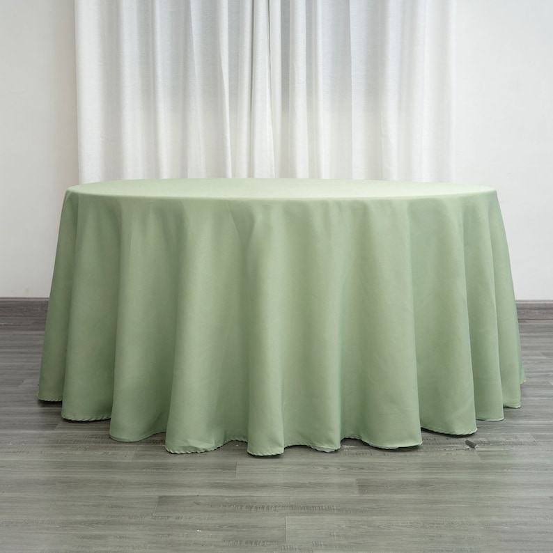 Op de afbeelding: Een ronde, saliegroene tafelkleed. Het tafelkleed is gemaakt van een gladde, kreukvrije stof.