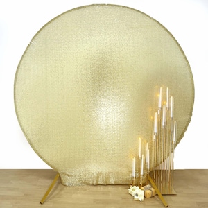 May include: A large, round, gold sequin backdrop with a matching gold metal stand. A gold candelabra with lit candles and small gift boxes are in front of the backdrop. The backdrop and candelabra create a festive, elegant display.