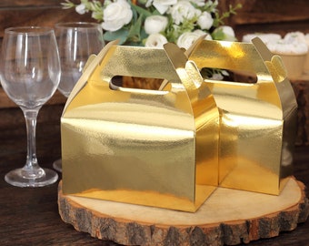 May include: Two gold favor boxes with handles on a wooden slice. The boxes are made of cardboard and have a shiny gold finish.
