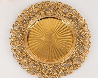 Könnte beinhalten: Ein goldfarbener dekorativer Platzteller mit einem verzierten, durchbrochenen floralen Design am Rand. Die Mitte des Tellers hat ein Sonnenstrahlenmuster. Der Teller ist wahrscheinlich aus Metall und dient dekorativen Zwecken.