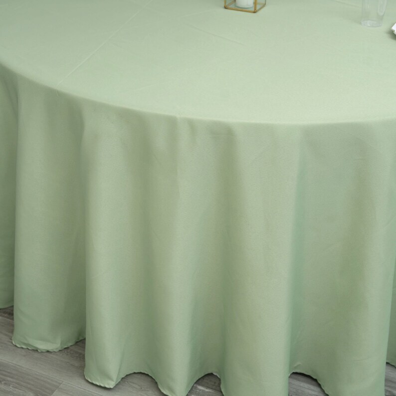 Op de afbeelding: Een ronde, lichtgroene tafelkleed. Het tafelkleed is glad en kreukvrij.