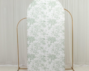 May include: A white arched backdrop with a green floral pattern. The backdrop is supported by a gold metal frame. The floral design features a repeating pattern of leaves and flowers. The backdrop is suitable for events and photo shoots.