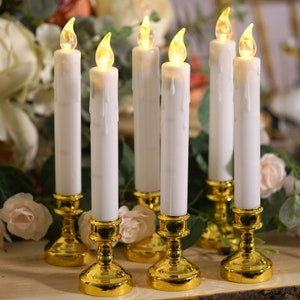 May include: Six white battery-operated pillar candles with a realistic dripping wax design. The candles are placed in gold metal candle holders.