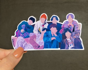 May include: A sticker featuring a group of seven cartoon figures sitting on a couch. The figures are wearing colorful clothing and have different hairstyles. The sticker is on a brown background.