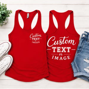 May include: Two red racerback tank tops featuring white screen-printed text that reads Custom TEXT or IMAGE. One tank top displays the text on the upper left chest, while the other displays larger centered text. The design is clean and bold.