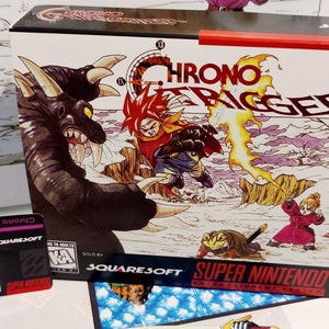 Puede incluir: Una copia en caja del juego de Super Nintendo "Chrono Trigger". La car&aacute;tula presenta una ilustraci&oacute;n din&aacute;mica de personajes en acci&oacute;n, con el t&iacute;tulo del juego en un lugar destacado. Tambi&eacute;n se ve una tarjeta m&aacute;s peque&ntilde;a con el t&iacute;tulo del juego.