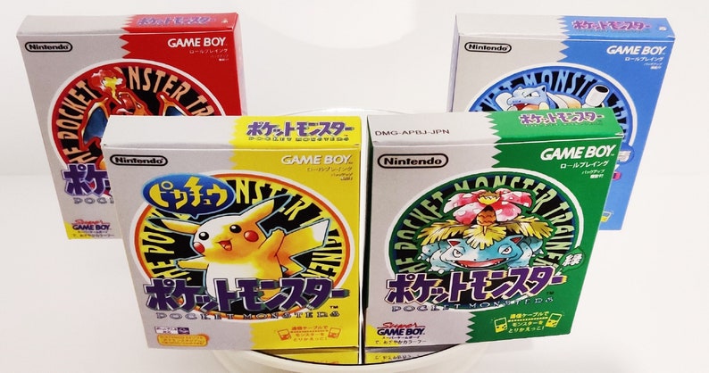 Pode incluir: Quatro vers&otilde;es diferentes do cl&aacute;ssico jogo Game Boy, Pocket Monsters, em sua embalagem japonesa original. As caixas s&atilde;o todas brancas com um design circular que apresenta um Pok&eacute;mon diferente em cada uma. As caixas est&atilde;o dispostas em semic&iacute;rculo sobre uma superf&iacute;cie branca.