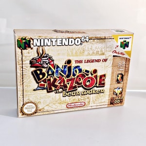 Könnte beinhalten: Eine Nintendo 64-Spielkassette für Banjo-Kazooie: The Bear Waker. Die Hülle ist beige mit einem braunen und goldenen Design. Der Spieltitel ist in rot und schwarzer Schrift. Die Hülle trägt ein Nintendo 64-Logo und ein "Only For"-Label.