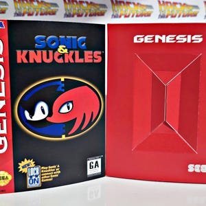 K&ouml;nnte beinhalten: Eine SEGA Genesis Videospielbox f&uuml;r Sonic & Knuckles. Die Box ist schwarz mit dem Spieltitel in Blau und Rot. Das Cover zeigt Sonic und Knuckles. Daneben eine rote Genesis-Box.