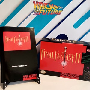 Puede incluir: Un cartucho de juego de Super Nintendo y un folleto de instrucciones para Final Fantasy II. La caja es roja con una espada dorada y el texto "Final Fantasy II" en blanco. El folleto de instrucciones es negro con un fondo rojo y el texto "Final Fantasy II" en blanco.
