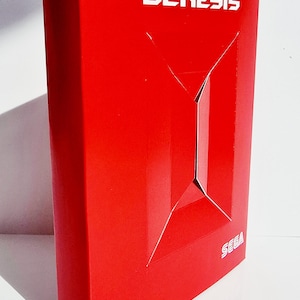 K&ouml;nnte beinhalten: Eine leuchtend rote Box mit dem Wort "GENESIS" in wei&szlig;er Schrift. Die Box hat ein geometrisches Design auf der Vorderseite und das SEGA-Logo ist sichtbar. Der Hintergrund zeigt die Worte "HACK TO FUTURE" in einem sich wiederholenden Muster.