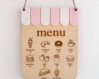 Puede incluir: Letrero de menú de café de madera con un diseño de toldo rosa y blanco. El menú presenta ilustraciones de varios alimentos, incluyendo un batido, croissant, donut, café, panqueques, fruta, papas fritas, hamburguesa, tostada y helado.