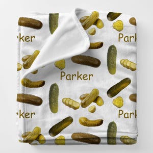 May include: A white ceramic mug with a black handle and the text "But First, Coffee" in a bold, black font. The mug is filled with a dark liquid, likely coffee, and sits on a light-colored surface.