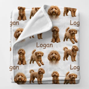 May include: White fleece blanket featuring a repeating pattern of brown dogs in various poses. The name "Logan" is printed in brown on the blanket. The blanket is soft and cozy, perfect for snuggling.