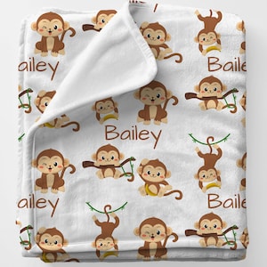 May include: White fleece baby blanket with a repeating pattern of brown monkeys in various poses. The blanket has the name "Bailey" printed on it in brown text.