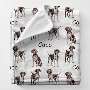 May include: A white ceramic mug with a black handle and the text "But First, Coffee" in a black, handwritten-style font. The mug is on a white surface.