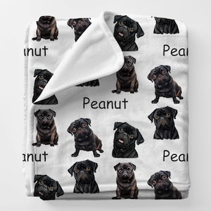 May include: White blanket featuring a repeating pattern of black pugs in various poses. The word "Peanut" is printed in black on the blanket. The blanket is made of a soft, plush material.