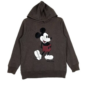 May include: A brown hooded sweatshirt with a vintage Mickey Mouse graphic on the front. The graphic is in black, white, and red. The text "Mickey Mouse" is printed below the graphic.