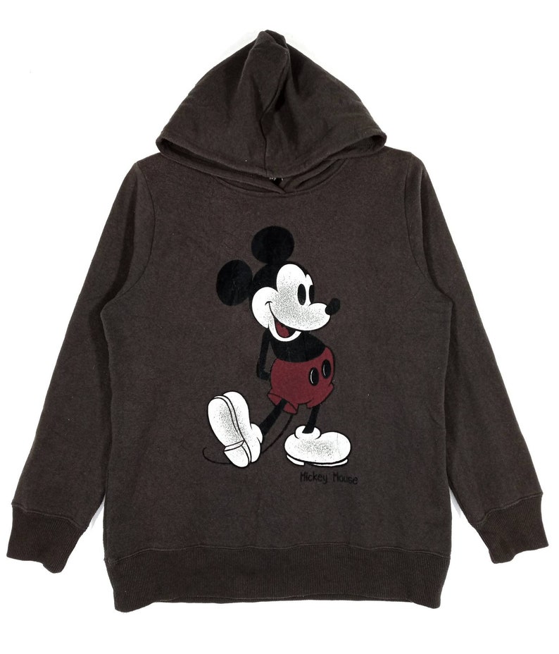 May include: A brown hooded sweatshirt featuring a vintage-style Mickey Mouse graphic on the front. The graphic is in black, white, and red. The text "Mickey Mouse" is printed below the graphic.