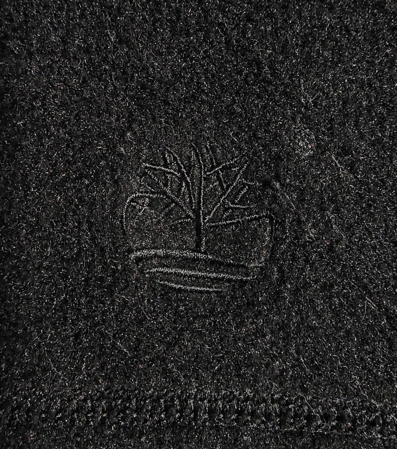 K&ouml;nnte beinhalten: Schwarze Strickm&uuml;tze mit einem kleinen gestickten Logo eines Baumes mit dem Wort "Timberland" darunter.
