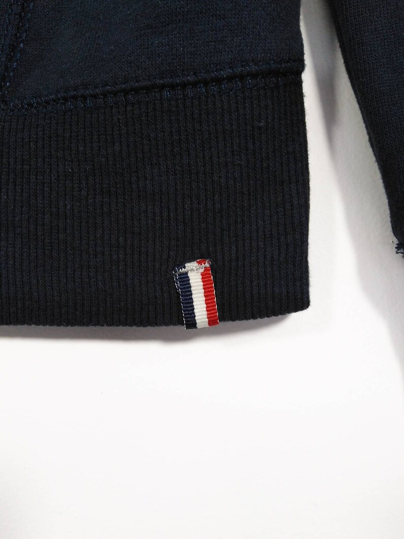 May include: A navy blue sweatshirt with a ribbed hem and a red, white, and blue striped label.