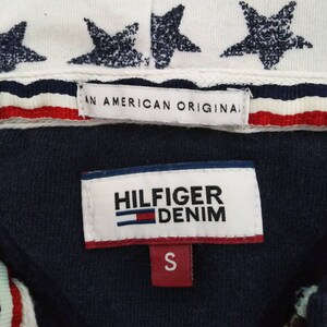 May include: A navy blue hooded sweatshirt with a white star print on the hood. The zipper is gold. The label reads "Hilfiger Denim" and "An American Original". The size tag says "S".