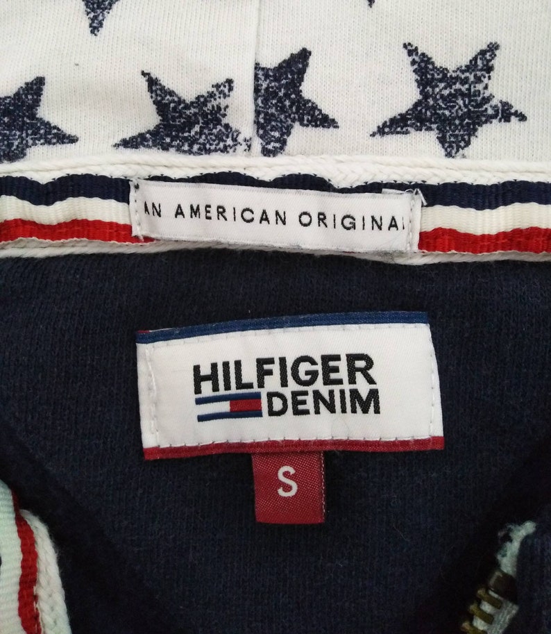 May include: A navy blue hooded sweatshirt with a white star print on the hood. The zipper is gold. The label reads "Hilfiger Denim" and "An American Original". The size tag says "S".