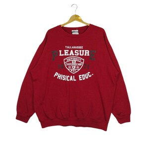 May include: Red sweatshirt with a white graphic print that says "Tallahassee University Pleasure Physical Educ." with a black and white logo in the center.