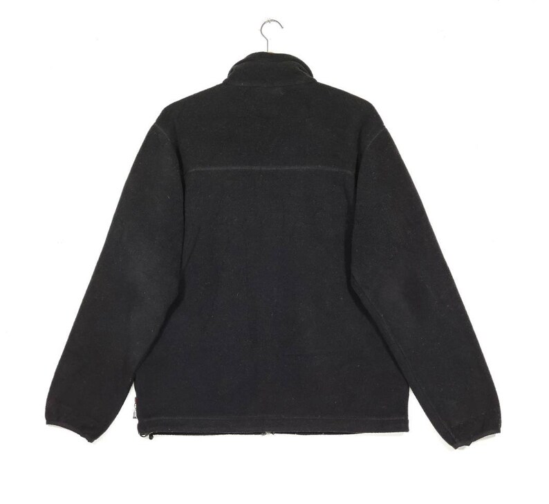 K&ouml;nnte beinhalten: Eine schwarze Fleecejacke mit Rei&szlig;verschluss und Stehkragen.