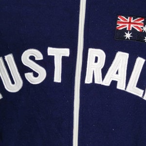 May include: A navy blue zippered jacket with white embroidered text that reads "AUSTRALIA" and a small Australian flag patch on the right side.