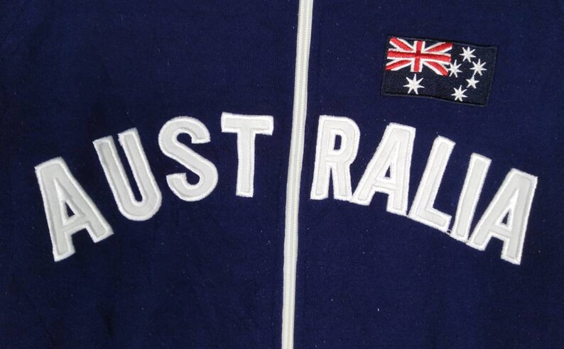 May include: A navy blue zippered jacket with white embroidered text that reads "AUSTRALIA" and a small Australian flag patch on the right side.