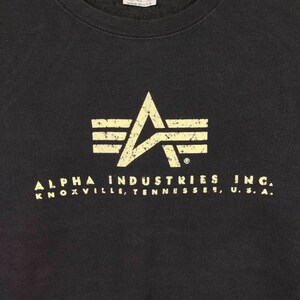 May include: Black sweatshirt with a distressed white logo of a winged star and the text "ALPHA INDUSTRIES INC. KNOXVILLE, TENNESSEE, U.S.A."