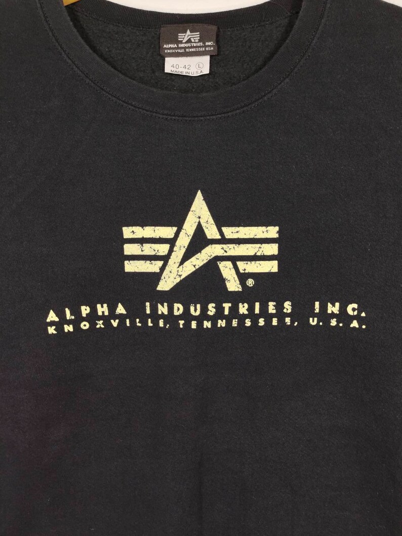 May include: Black sweatshirt with a distressed white logo of a winged star and the text "ALPHA INDUSTRIES INC. KNOXVILLE, TENNESSEE, U.S.A."